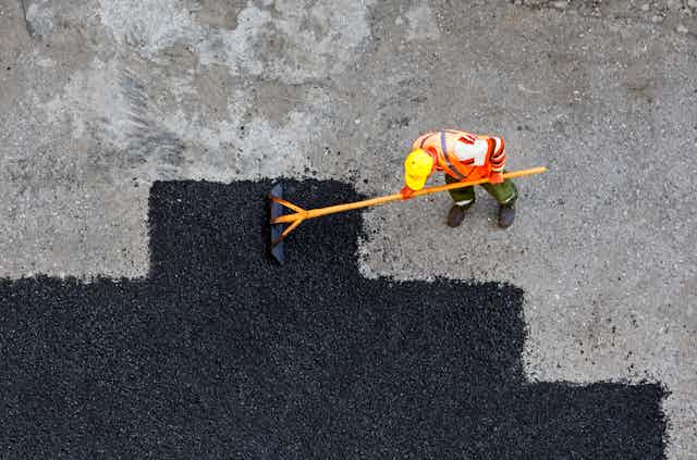 Aerial view of worker repairing road surface.