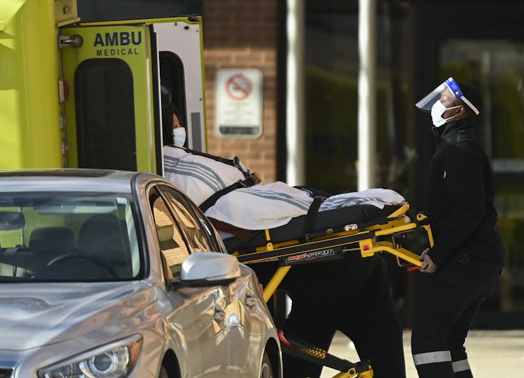 A person on a stretcher is placed into the back of an ambulance.