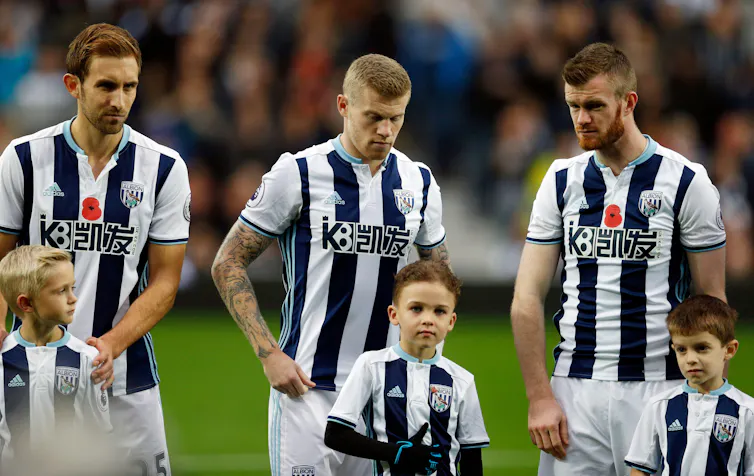 James McClean stands between two teammates, without a poppy on his black and white shirt.