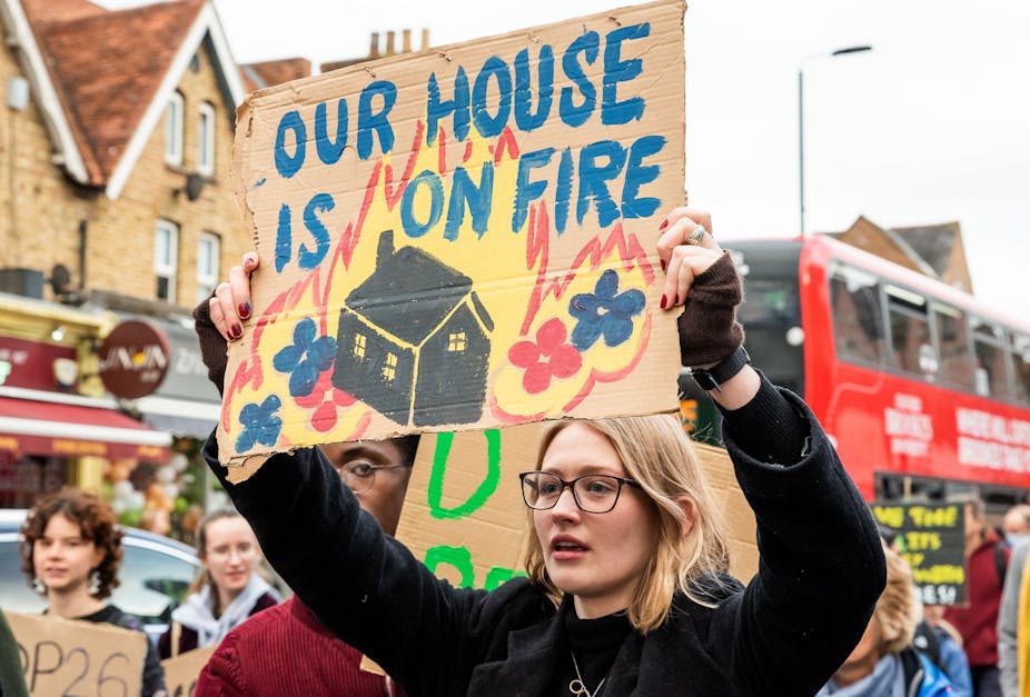 Woman holds up banner saying 'our house is on fire'