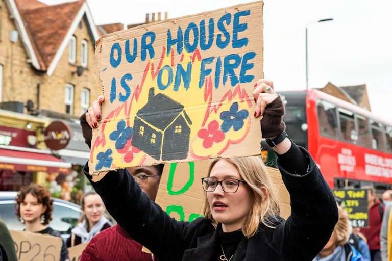 Woman holds up banner saying 'our house is on fire'