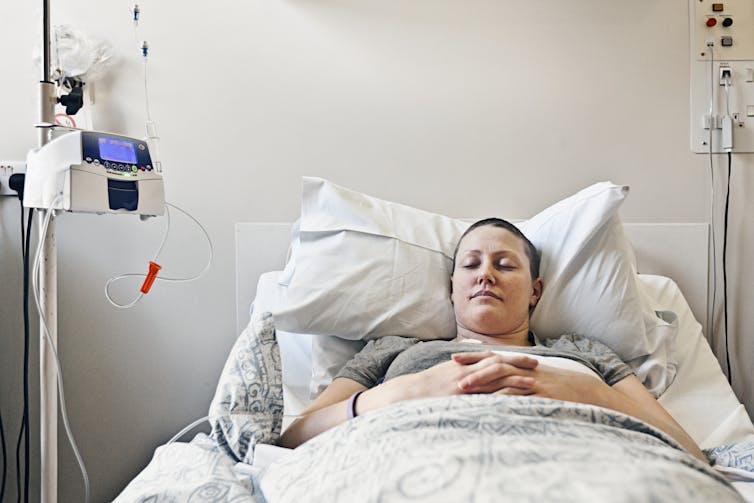 Cancer patient lying on hospital bed receiving chemotherapy.
