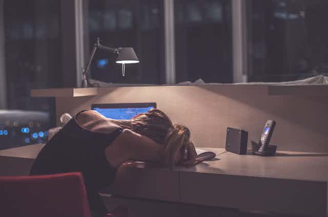 Exhausted female student falls asleep at desk while studying at night