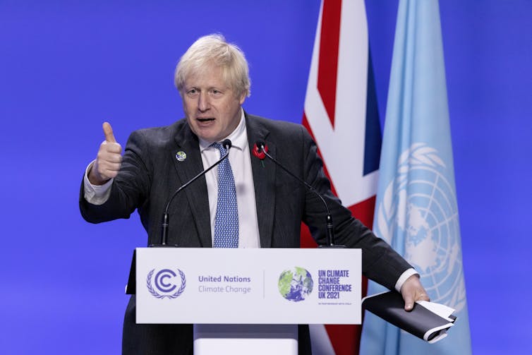 man at lectern gives thumbs up