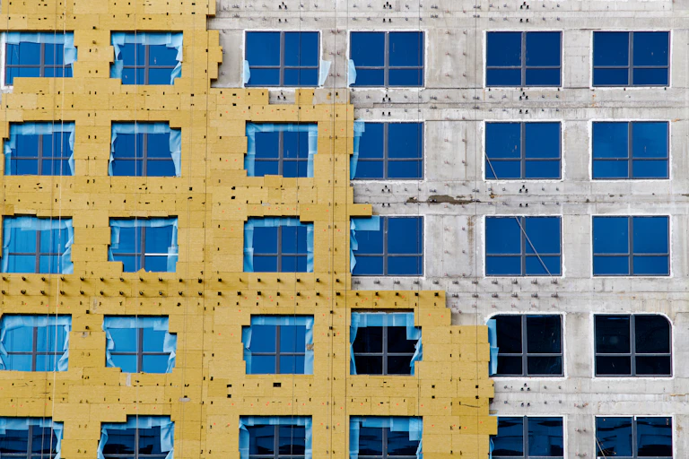 Exterior wall in process of construction shown. Yellow insulation covers the left of the building.