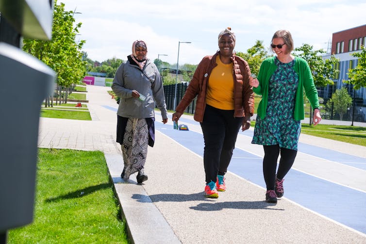 Three people walk along a street