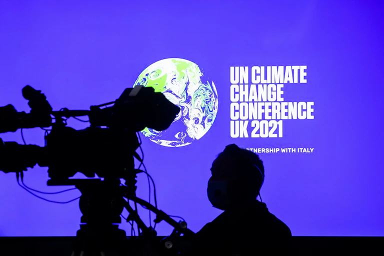 Cameraman stands in front of COP26 screen