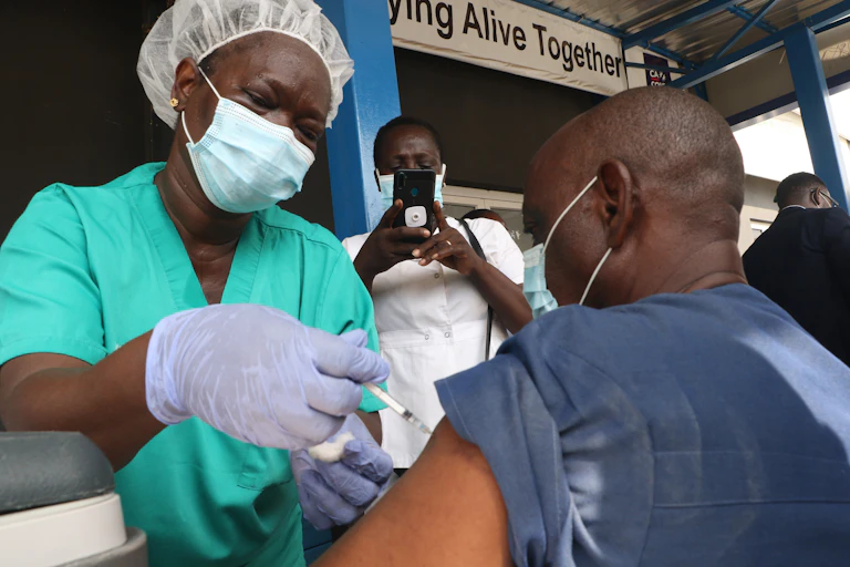 Nurse vaccinating a man while someone takes a picture