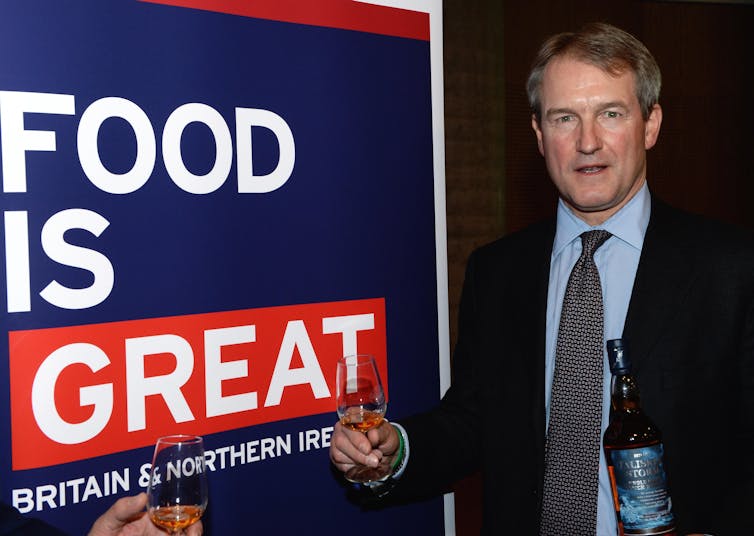 Owen Paterson holding a glass of wine at an event.