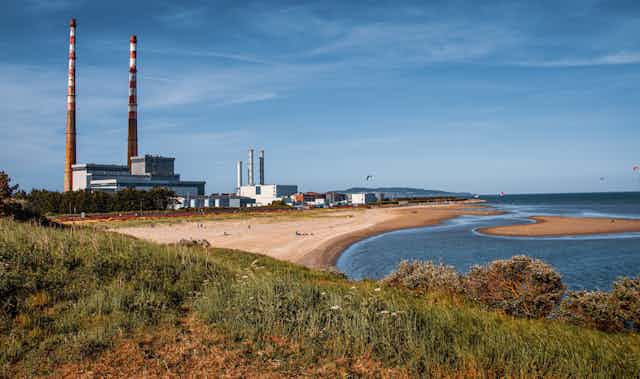 Coastline with sandy beach and large industrial chimneys 
