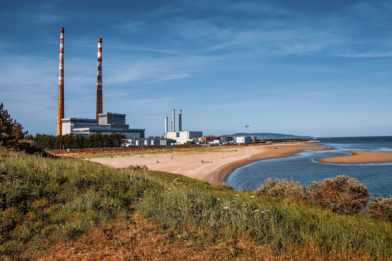 Coastline with sandy beach and large industrial chimneys