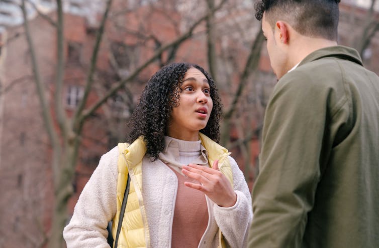 A woman looks up at a man as they argue.