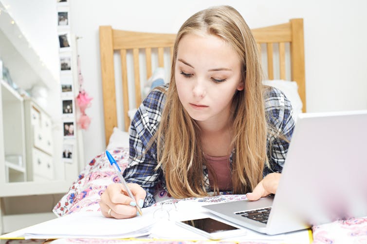 Girl studying on her bed.