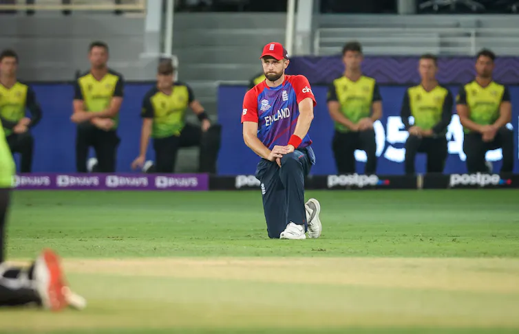 England cricketer Chris Woakes takes the knee before a T20 World Cup match against Australia. In the background the Australian teams also takes the knee.