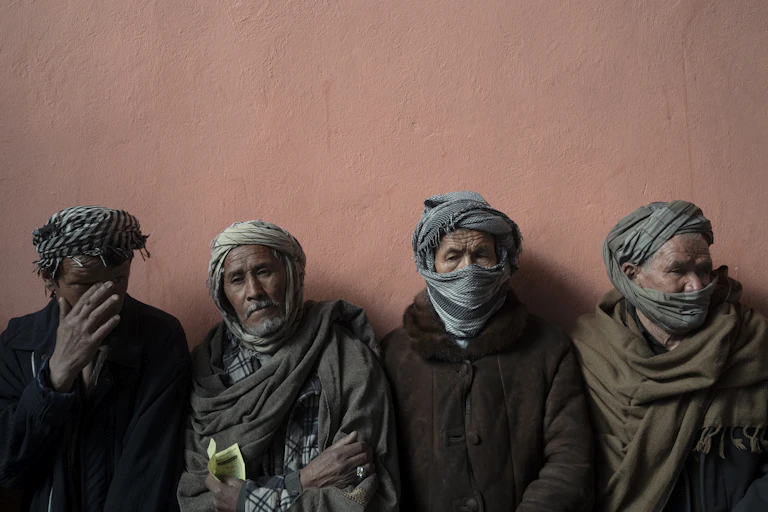 Four men in scarves huddle together in a line.