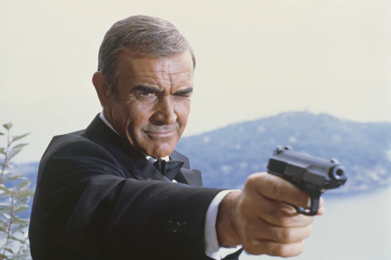 Man in suit points a gun.