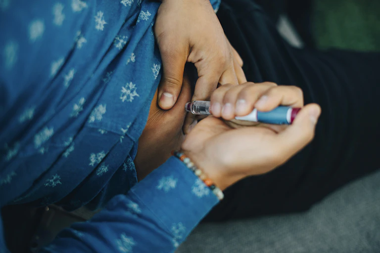 Person injecting insulin in abdomen.