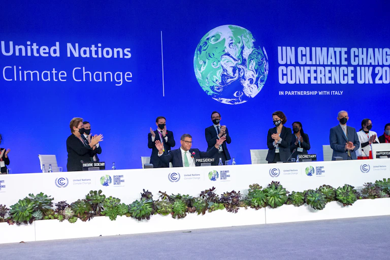 Delegates stand and applaud the president of COP26.