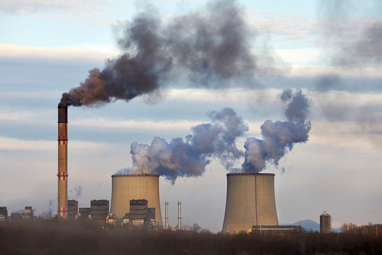 Black smoke rising from power plant chimneys.