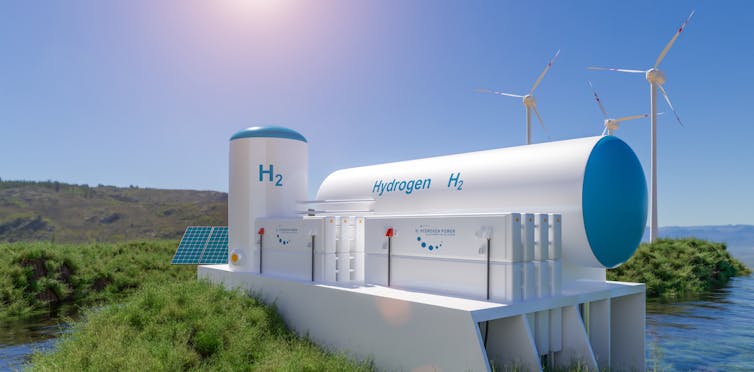 A tank of hydrogen on a cliff next to wind turbines.