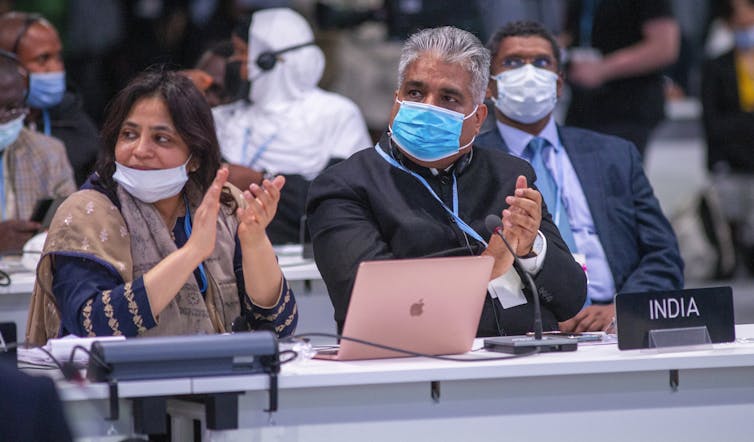 man and woman in face masks clap