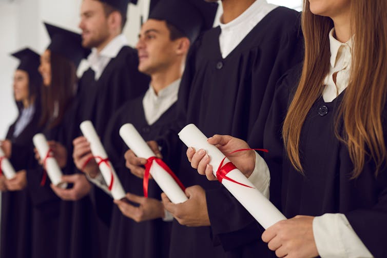 Line of graduates holding their degree certificates