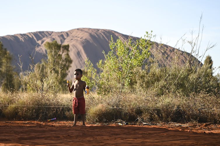 A local child plays in front of Uluru