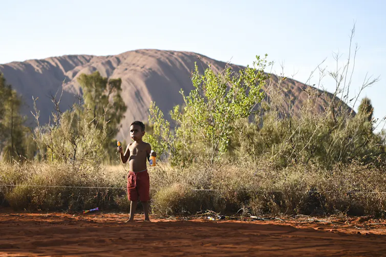 A local child plays in front of Uluru