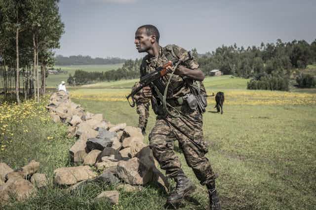Soldat éthiopien en train de courir avec son fusil en main dans une prairie.