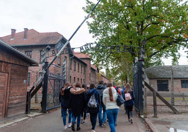 Group of students passing under "Arbeit Macht Frei" sign at Auschwitz