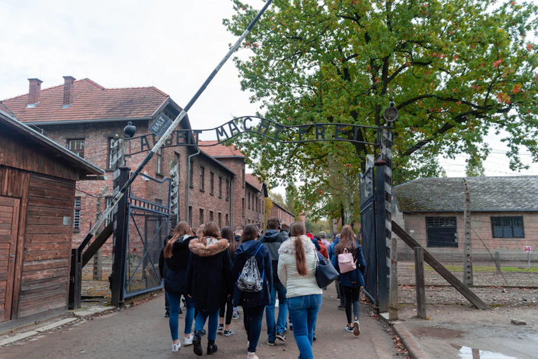 Group of students passing under "Arbeit Macht Frei" sign at Auschwitz