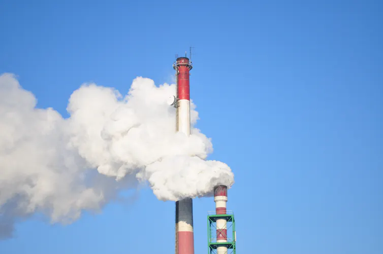 Two industrial towers release smoke into the sky.