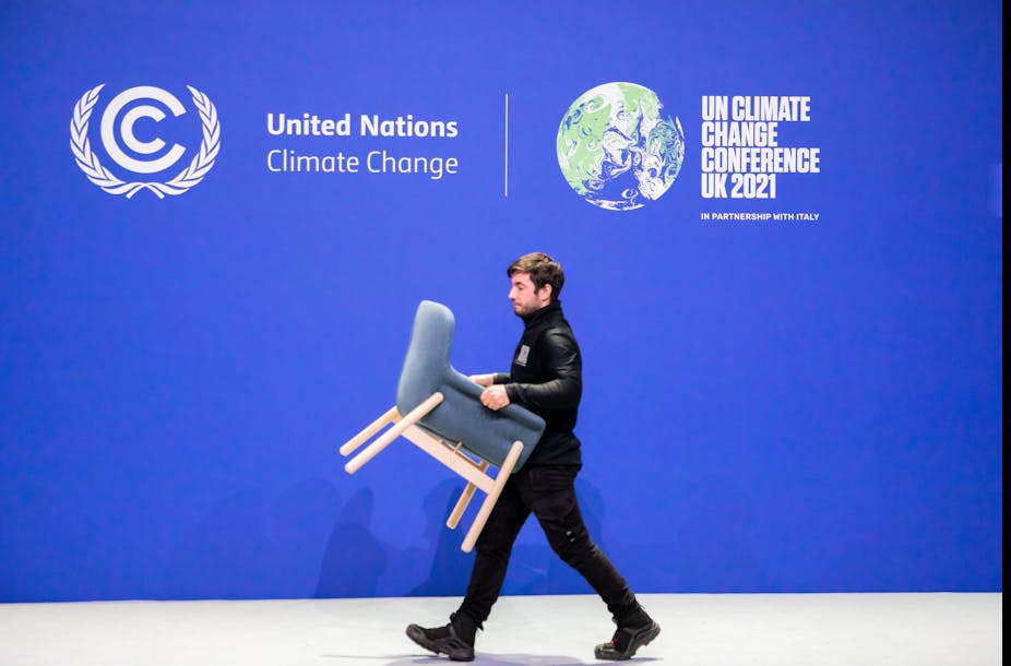 man carries chair in front of UN climate conference banner