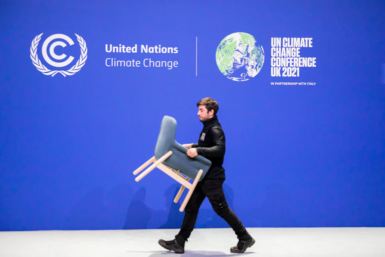 man carries chair in front of UN climate conference banner