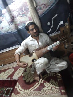 Man playing a stringed instrument.