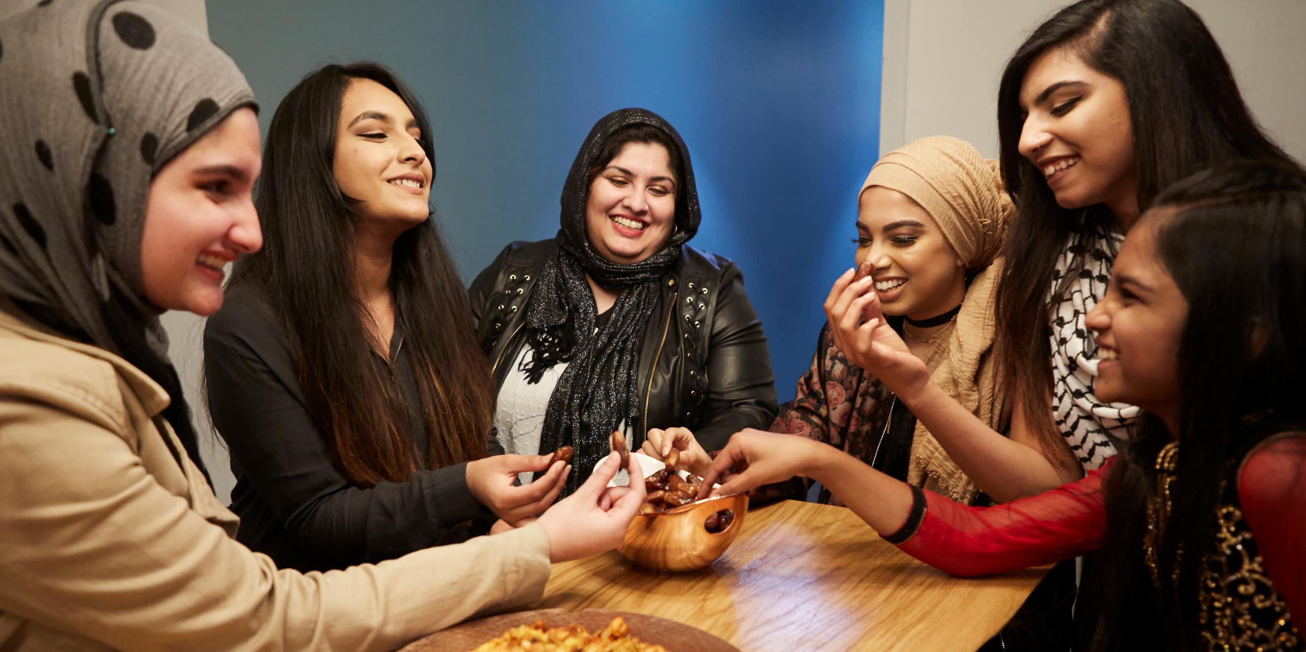 Six girls sitting around a table, sharing food as they break fast during the month of Ramadan