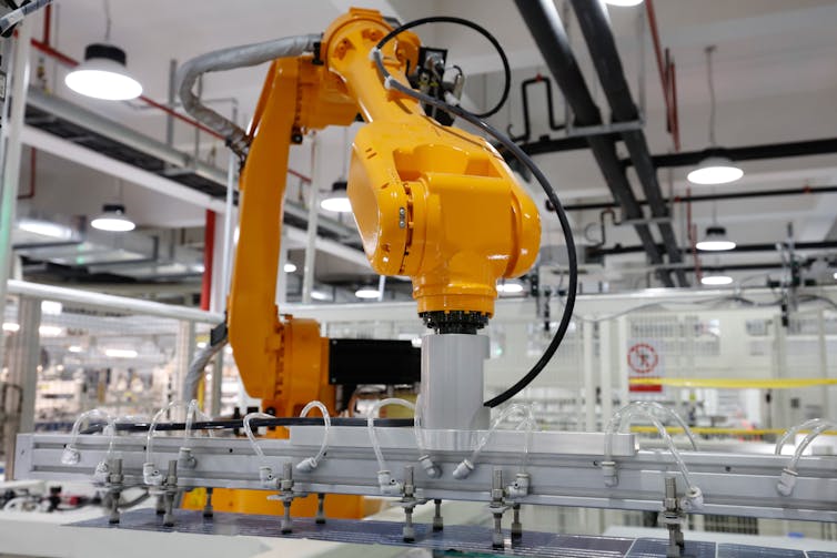 A yellow robotic arm assembles a solar photovoltaic panel