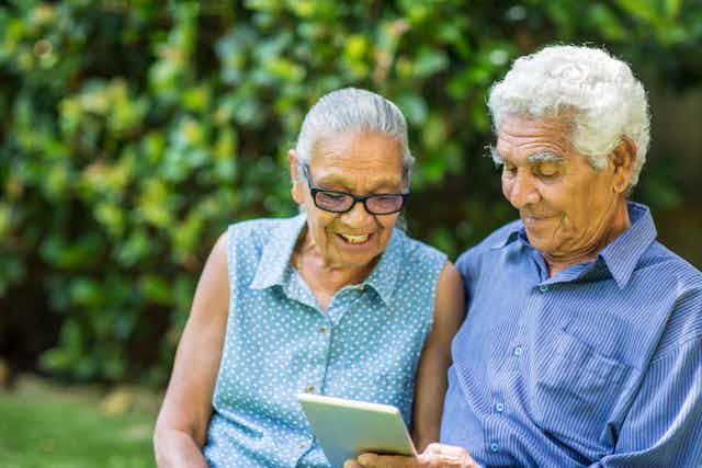 An elderly couple are looking at a tablet.