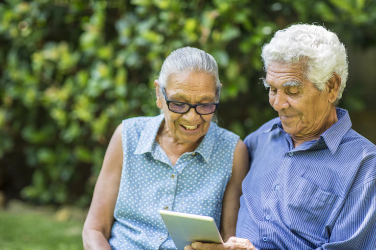 An elderly couple are looking at a tablet.