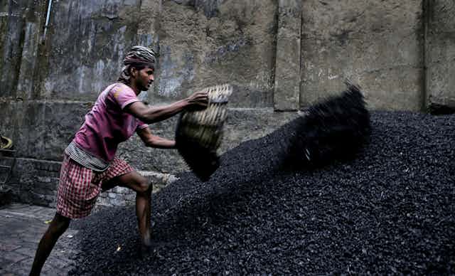 A worker throws coal chips onto a stockpile.