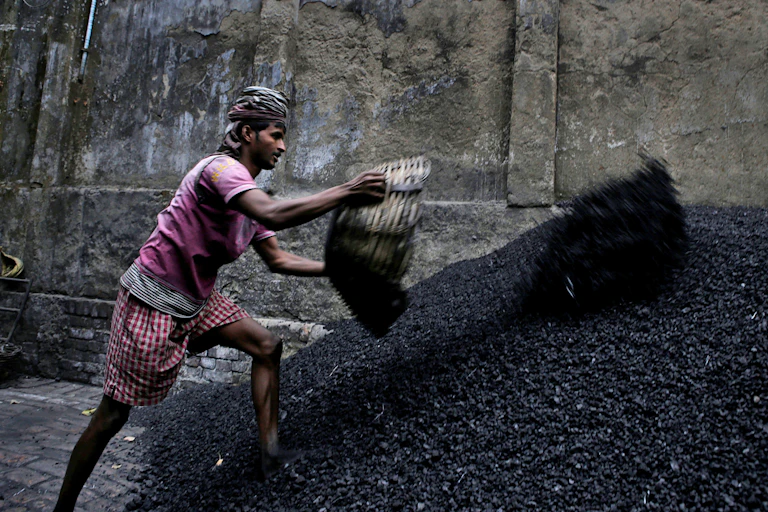 A worker throws coal chips onto a stockpile.