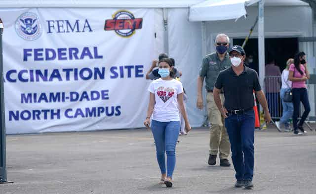 People with masks walking away from a vaccination site.