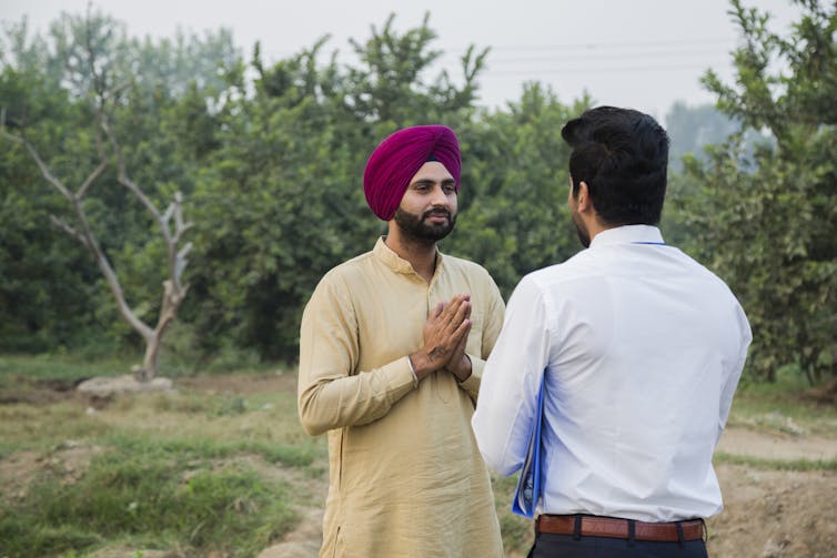 A Sikh man folding hands in a namaste before another man.