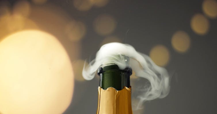 An open champagne bottle emits fizz and gas.