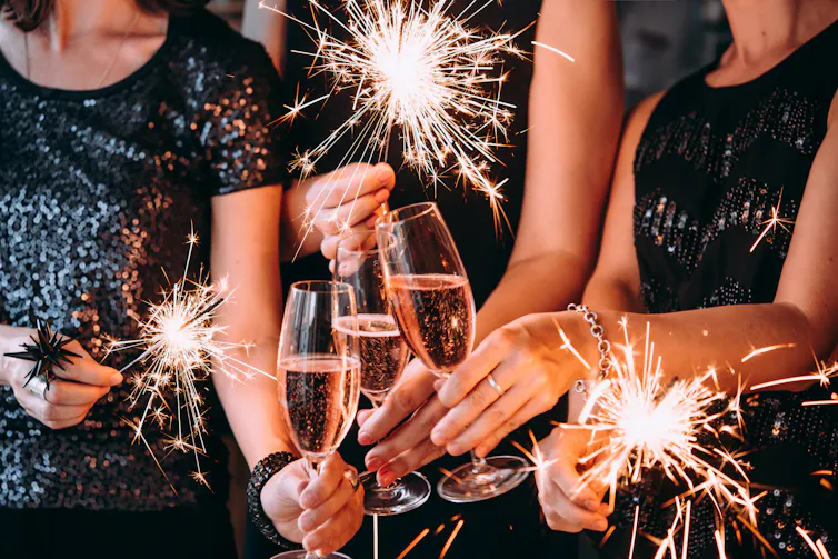 People clink champagne glasses together at a party.
