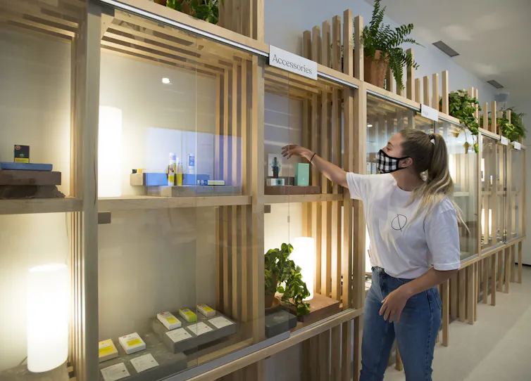 An employee arranges a variety of products at a cannabis store.