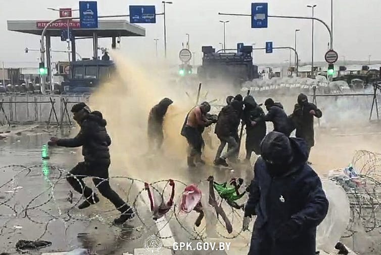 Polish forces using water cannons against migrants.