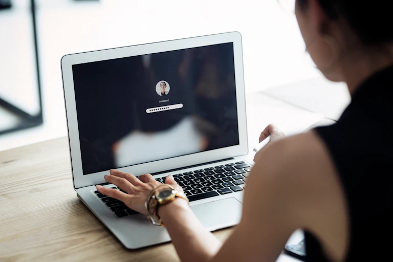 A woman types a password on a laptop.