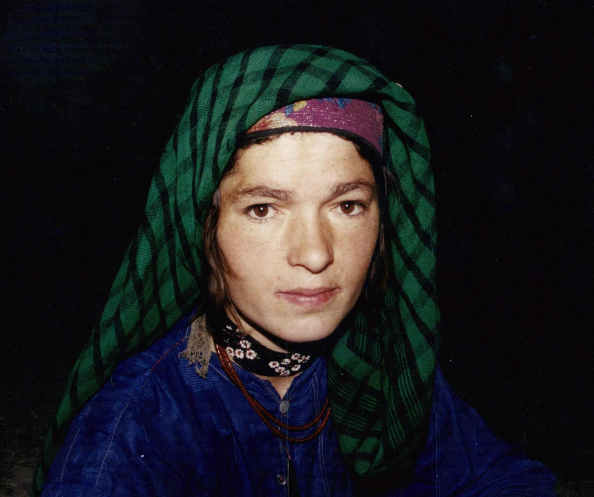 Close up of a woman wearing a green headscarf against the night sky.