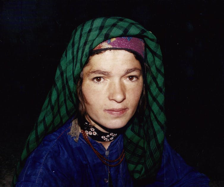 Close up of a woman wearing a green headscarf against the night sky.